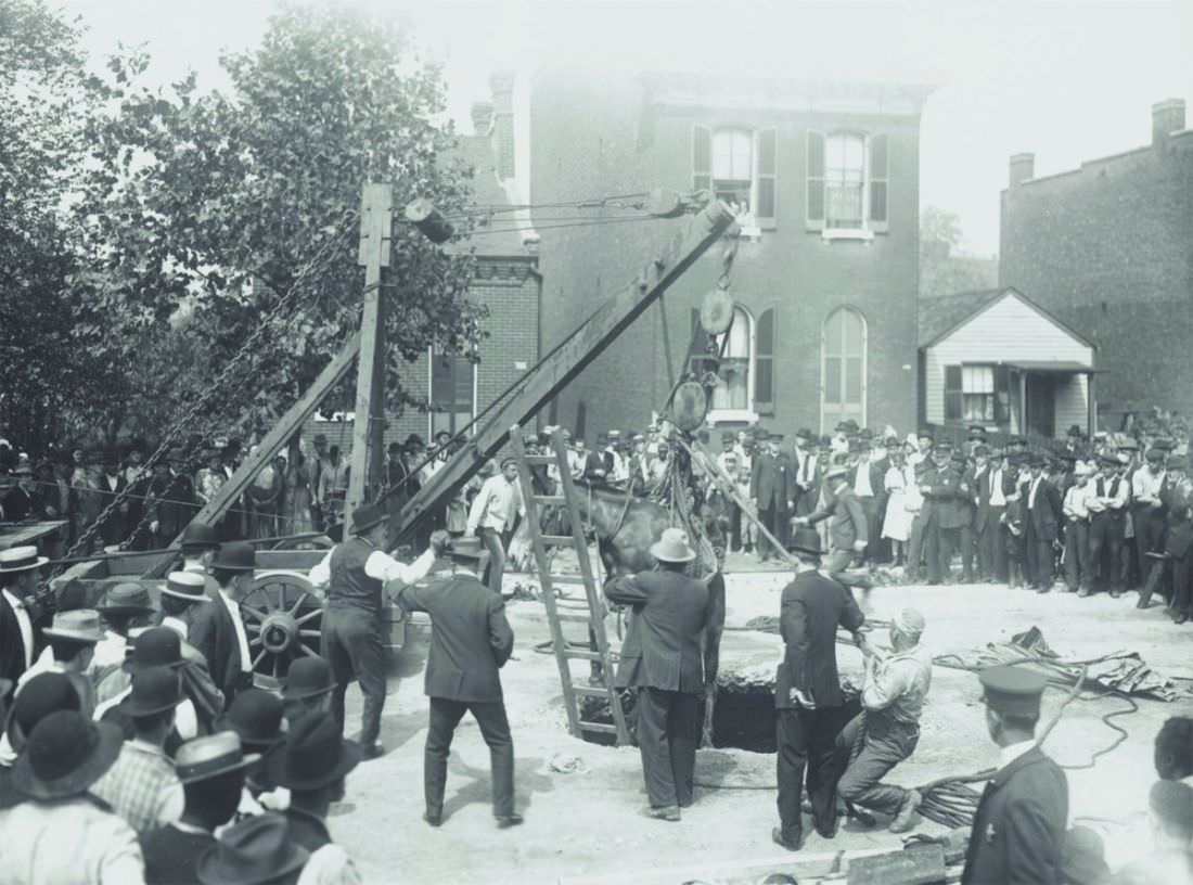 Crowd watching a horse being pulled out of a hole. Photograph, 1910–1920.