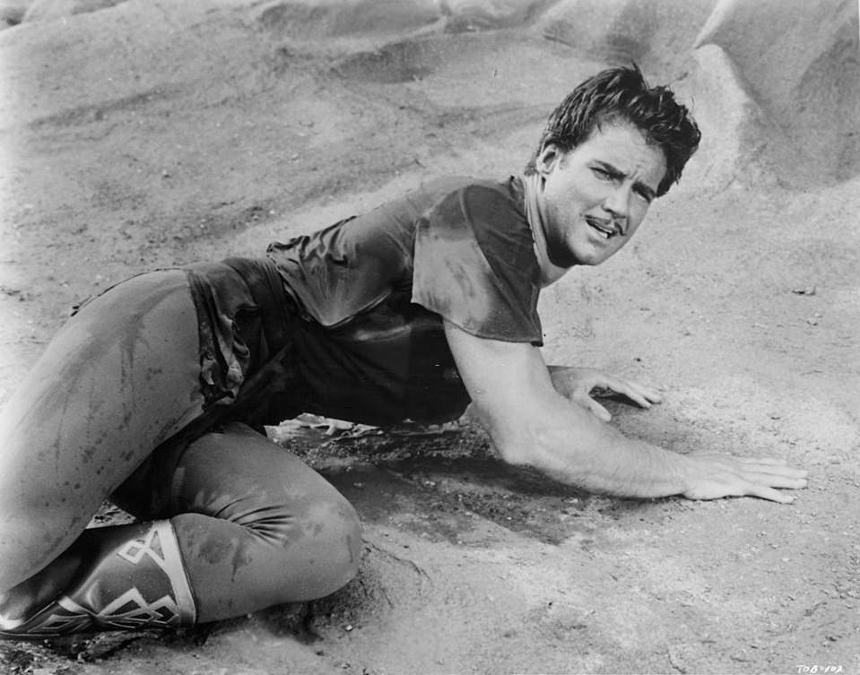 Steve Reeves laying in the sand in a scene from the film 'The Thief Of Baghdad', 1961