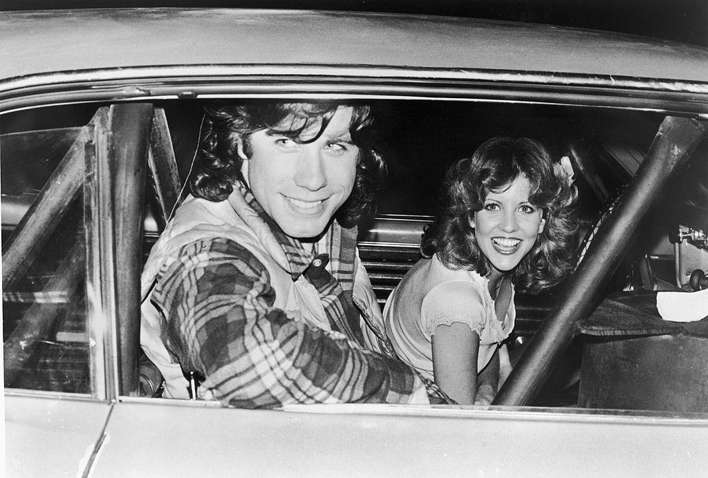 John Travolta with Nancy Allen pose in a car on the set of the film, 'Carrie,' directed by Brian De Palma, 1976