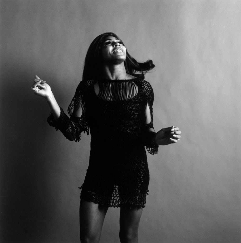 Tina Turner wearing a dark crocheted mini-dress, looking up and snapping her fingers while singing, New York City.