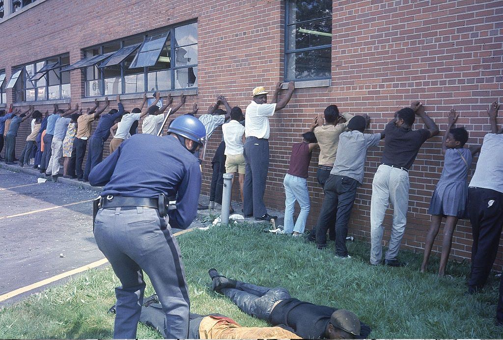 Policeman lining up suspects after race riots, 1967