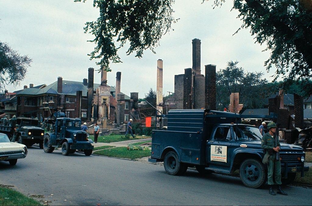Soldiers patrol along row of fire-gutted homes following the riot, Detroit, 1967