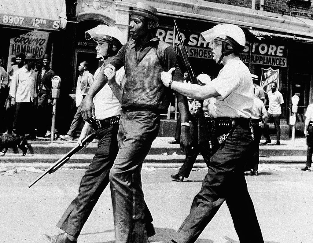 Két rendőrtiszt, teljes lázadó felszereléssel, letartóztat egy fekete embert egy lázadás és fosztogatás kitörésekor, Michigan, Detroit nyugati oldalán, 1967. július 23.
