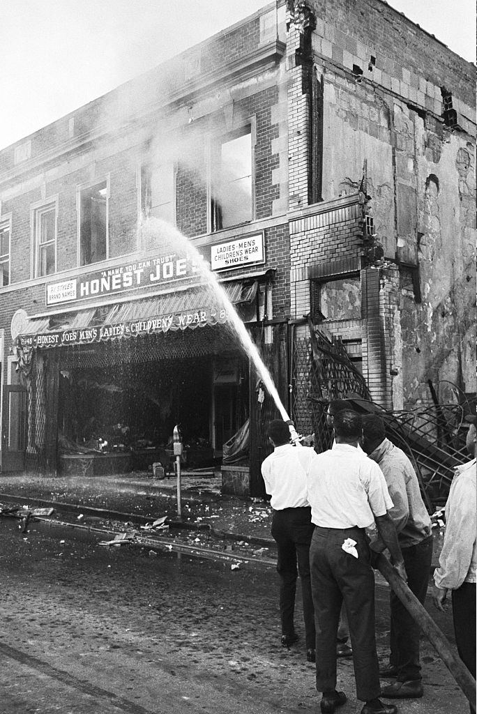Detroiti fekete lakosai a tűzoltókkal eldobott tűzoltócsöveket vesznek fel, hogy tűzoltásra szomszédságukban kerüljön sor, 1967
