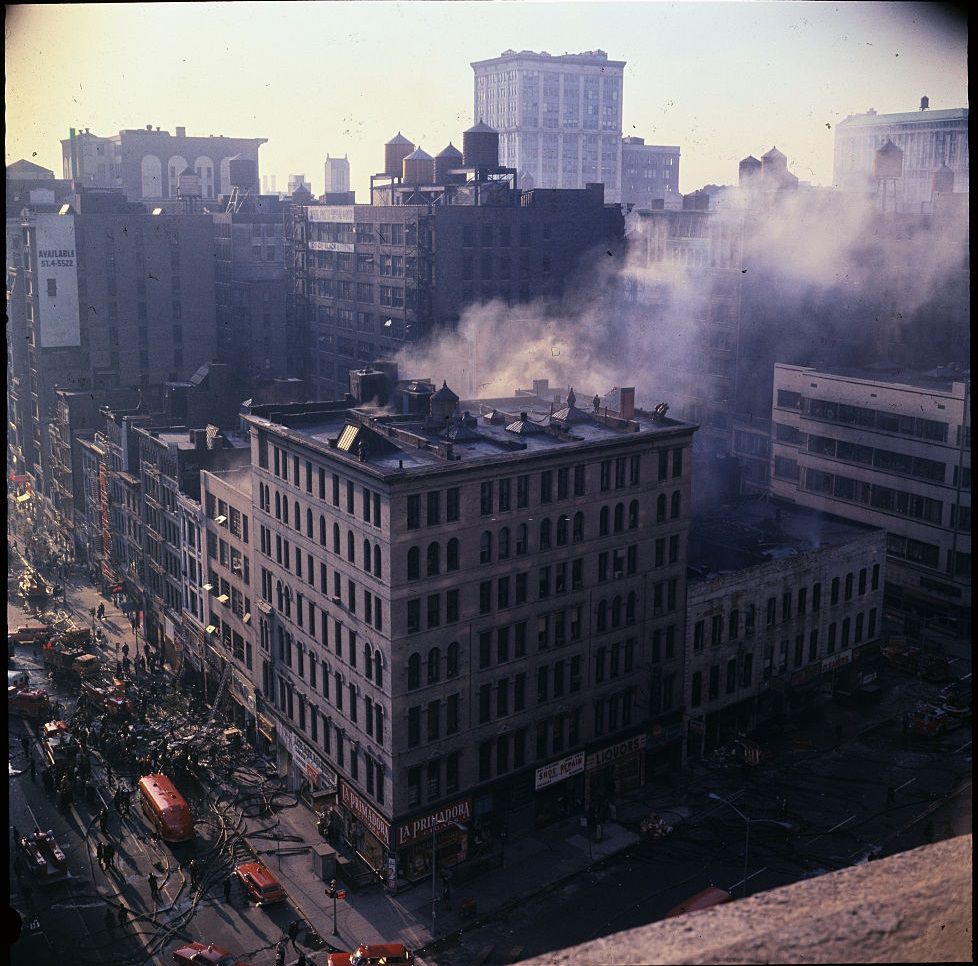 Itt lángok látszanak az épületből, amikor a tűzoltók a tömlőt lecsempézték a szerkezetre, Detroitban, 1967