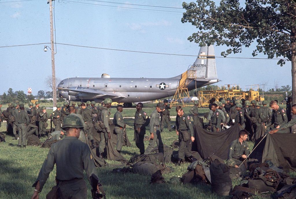 US National Guard troops as they sort equipment in a field near a Lockheed C-130 Hercules transport plane, Detroit, 1967