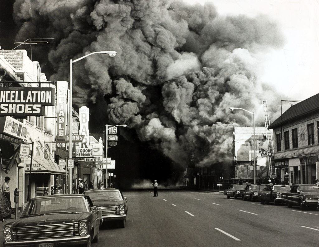 A huge pall of smoke pours from a burning building during race riots in the city, 1967