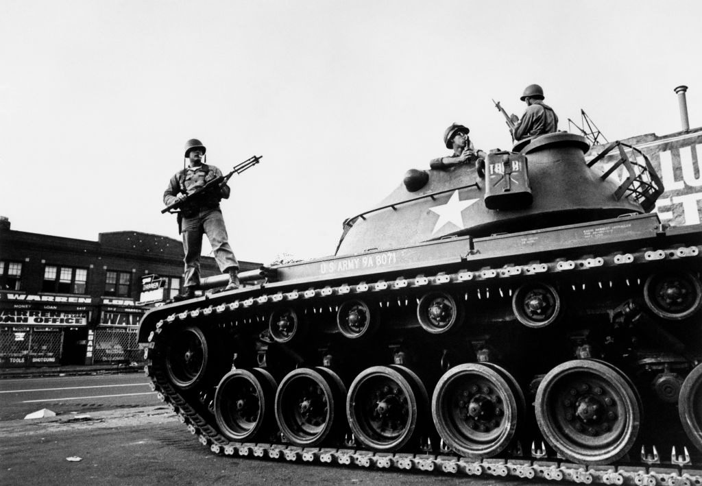 Federal soldiers stand guard on a tank in a Detroit street on July 25, 1967 during riots, 1967