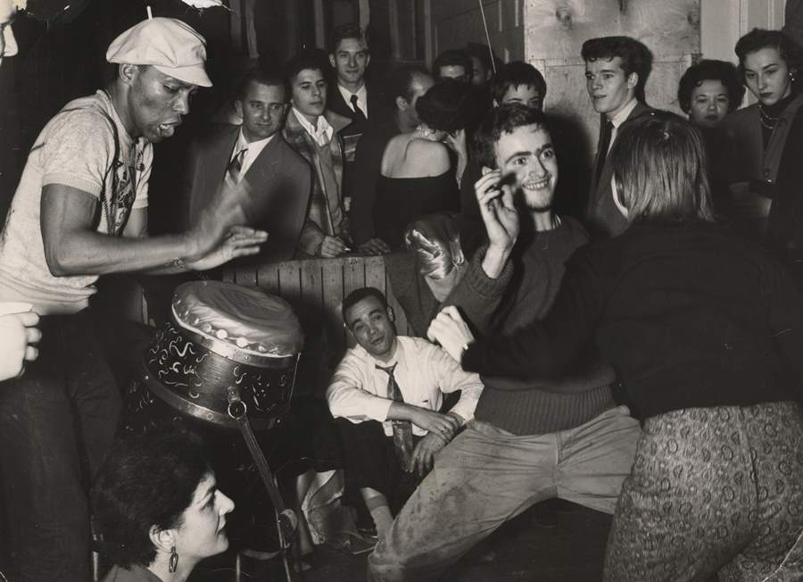 A woman and man dance to the accompaniment of a drummer beating on congas at a party in Greenwich Village in 1956.