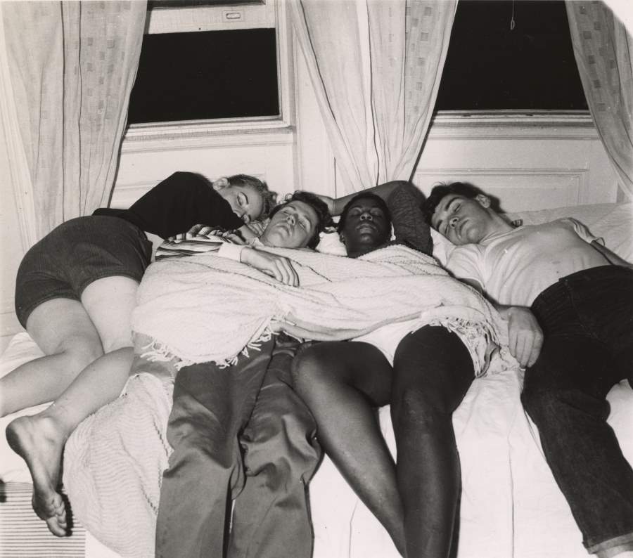 Four friends share a bed in a Greenwich Village apartment after a long night out in 1956.