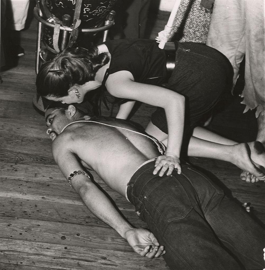 Ted Joans, Beat Generation poet, painter, and musician, in a Voodoo trance, lying shirtless on a wooden floor, 1960