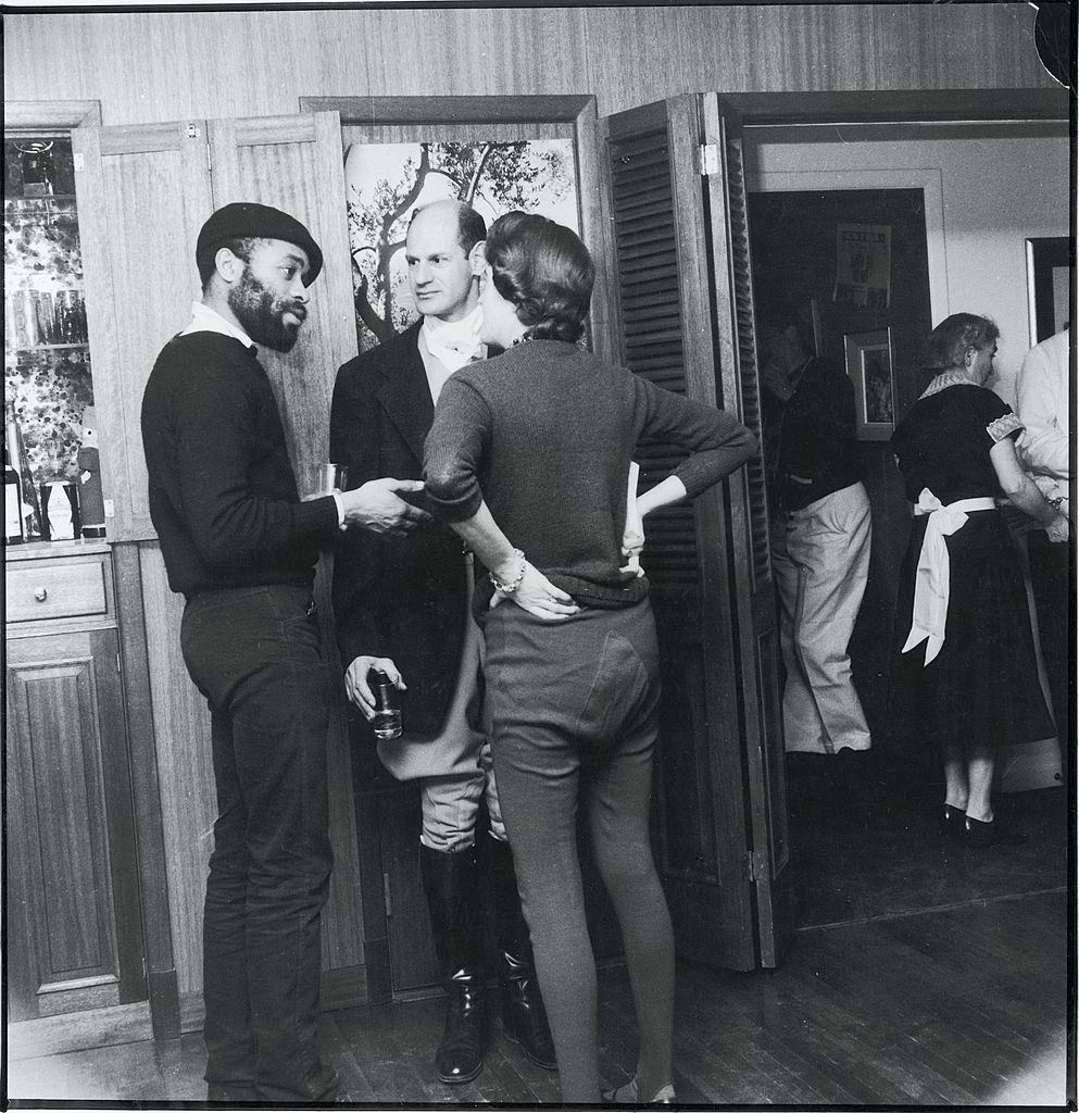 Dressed in black, female attendees at a 'Rent-a-Beatnik' party smoke at the top of a staircase in a townhouse in Sniffen Court, New York, 1960