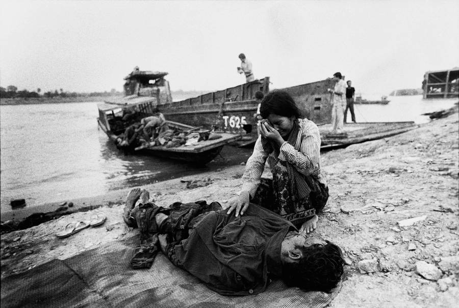 Egy elrontott nő sír a férje teste felett, amelyet Phnom Penh khmer Rouge katonák öltek meg.  1975.