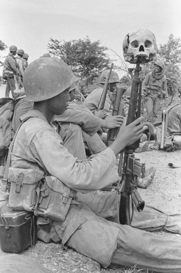 A child soldier with a human skull resting on the tip of his rifle, Dei Kraham, Cambodia. 1973.