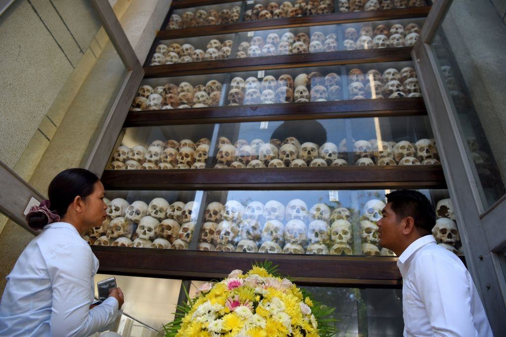 People looking at skulls displayed in a stupa during the annual 'Day of Remembrance' at the Choeung Ek killing fields memorial in Phnom Penh