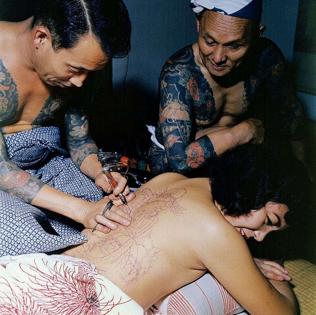 Japanese tattoo artist, Tokumitsu Uchida tattooing back of a woman, 1955