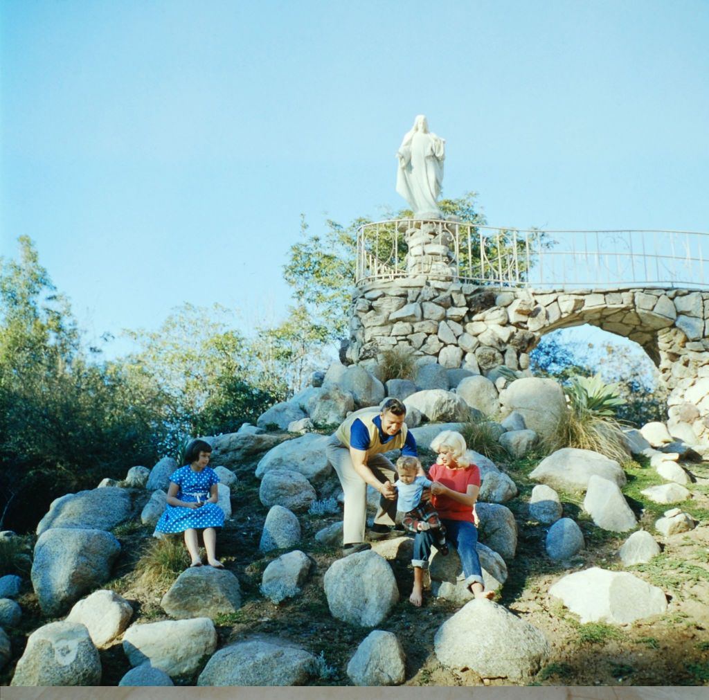 Jayne Mansfield with her husband and son, sitting on the rocks above their backyard heart-shaped pool of their Pink Palace