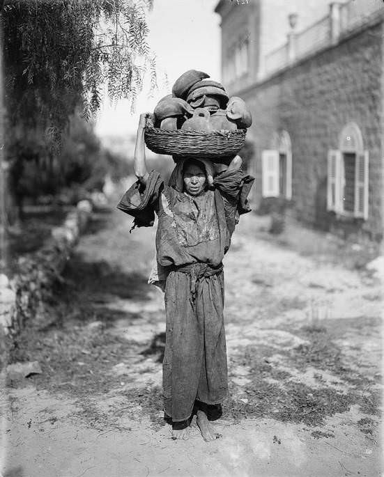 A woman carries her wares to the marketplace, Circa 1898-1914