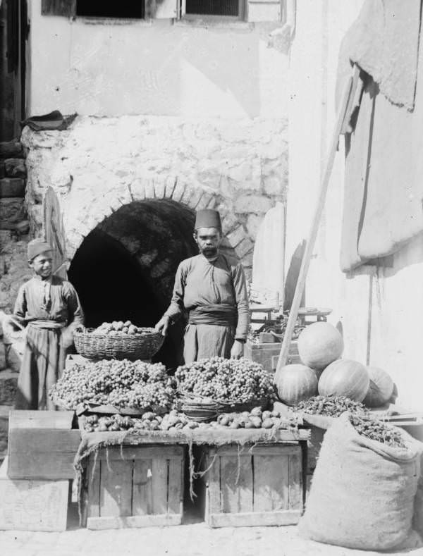 A fruit vendor displays his goods, Circa 1900-1920
