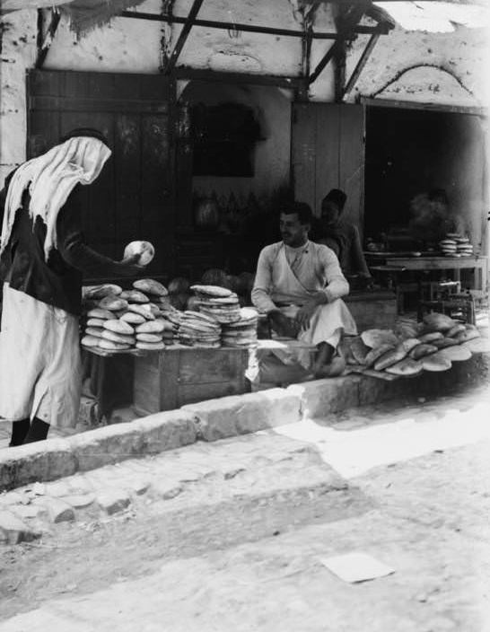 A woman barters over the price of bread, Circa 1900-1920