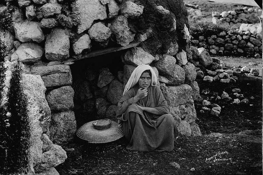 A woman sits in front of the village oven, Circa 1898-1914