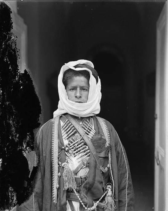 A young Bedouin boy wearing a cartridge belt, Circa 1898-1914