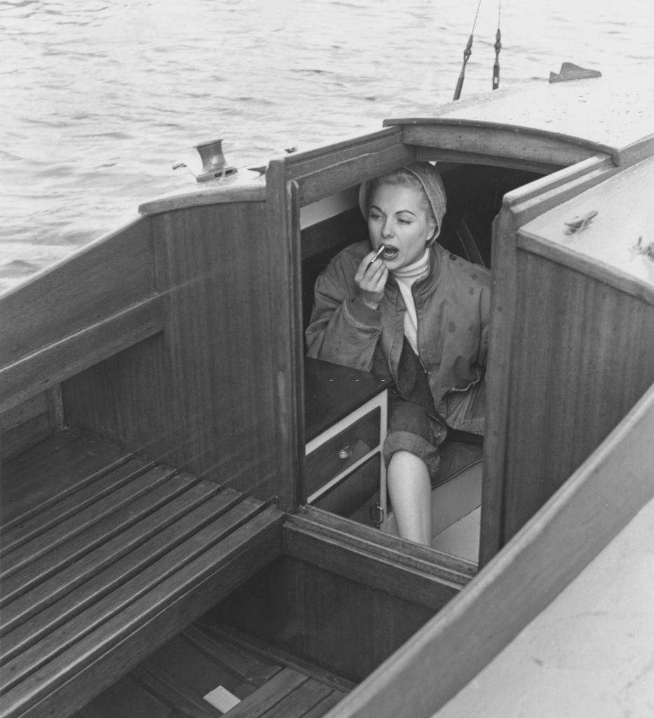 Martha Hyer applying lipstick on board a yacht, circa 1955