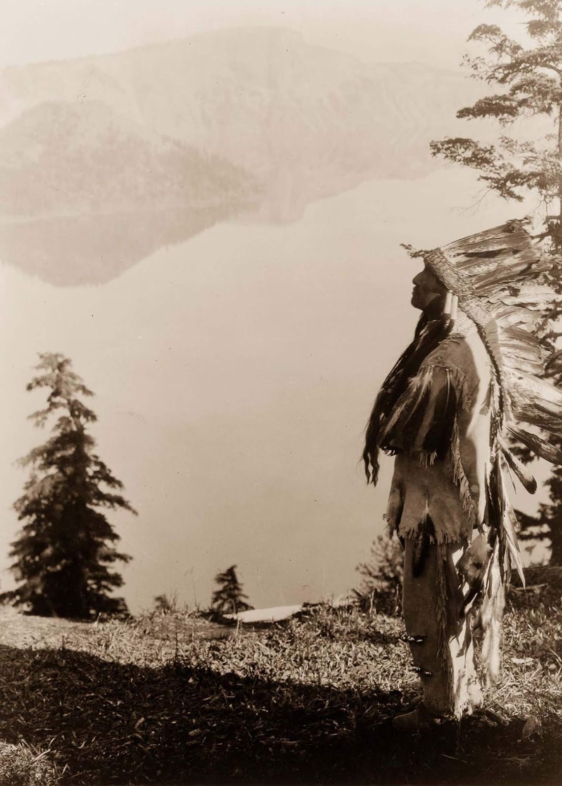 A Klamath chief stands on a hill above Crater Lake, Oregon. 1923.