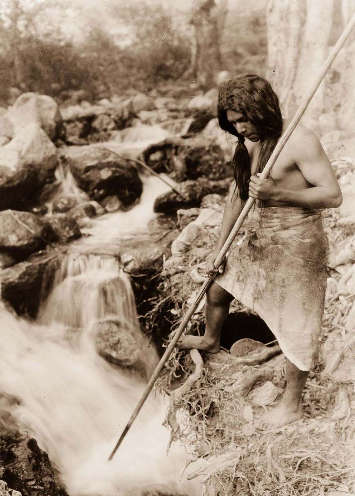 A Hupa spear fisherman watches for salmon. 1923.