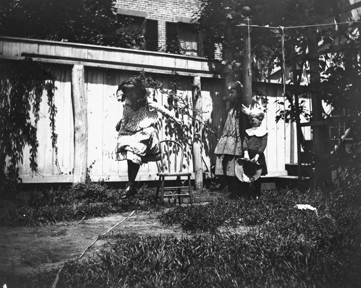 Mildred Grimwood jumps in the backyard at 314 Livingston Street as brother Victor Grimwood and pal Zelma Levison look on.June 20, 1886