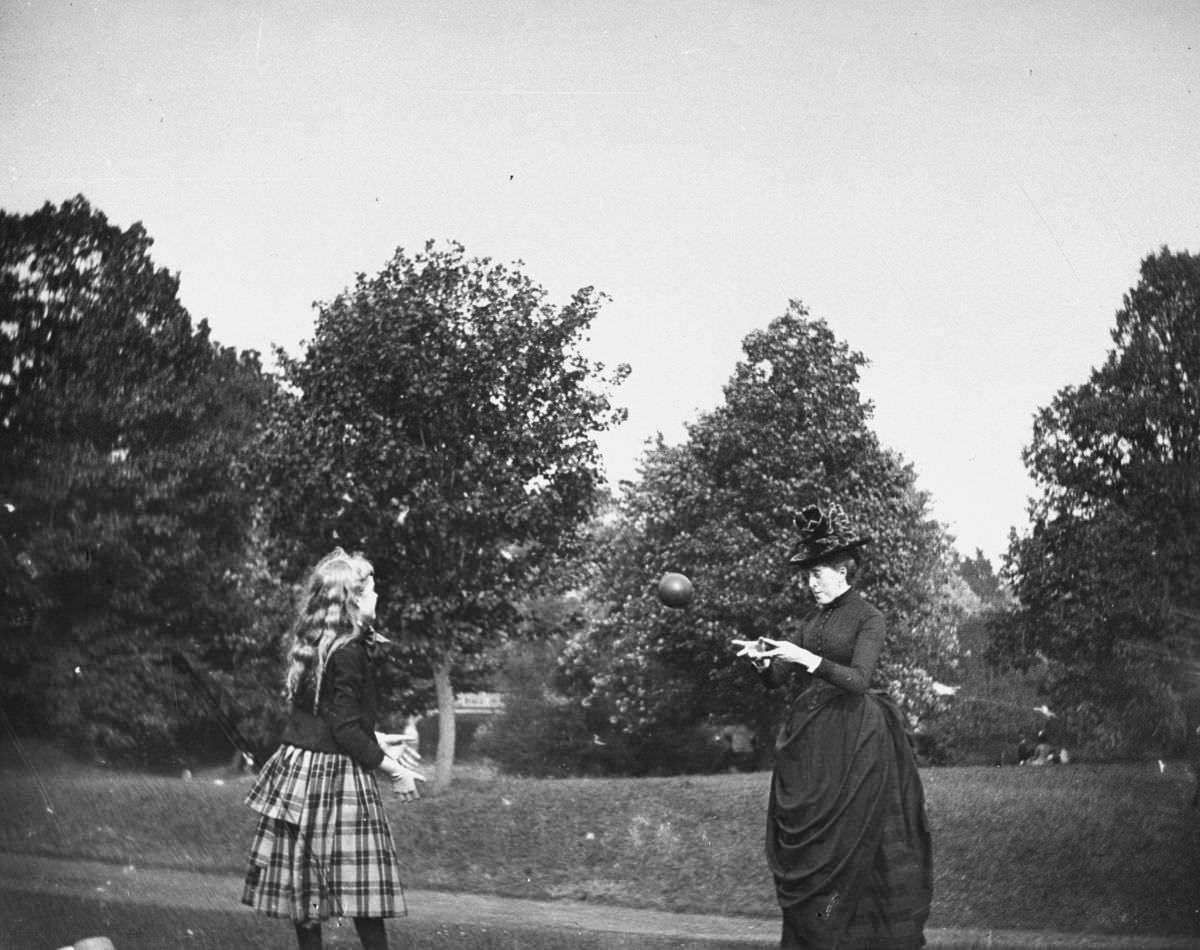 Zelma Levison and her aunt Jo Grimwood throw a ball back and forth on a lawn in Prospect Park.July 20, 1886