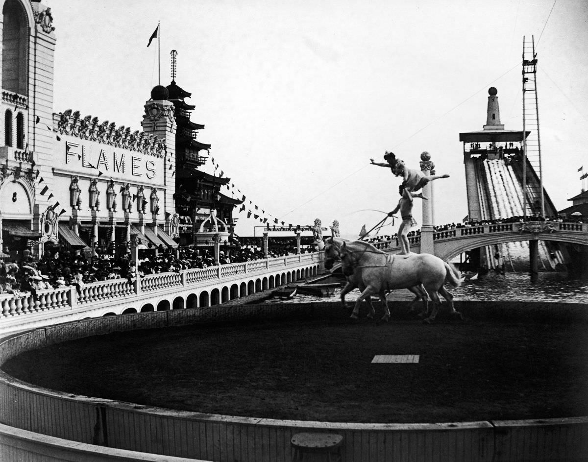 Acrobats perform a balancing act on the backs of a pair of horses as crowds watch at Coney Island’s Dreamland