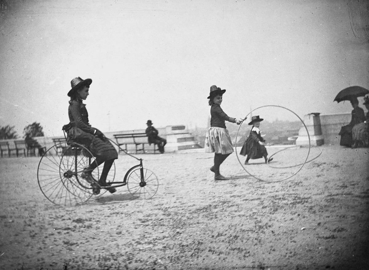 Isabel Harter rides a tricycle while her sister Nellie rolls a hoop in Fort Greene.May 22, 1886