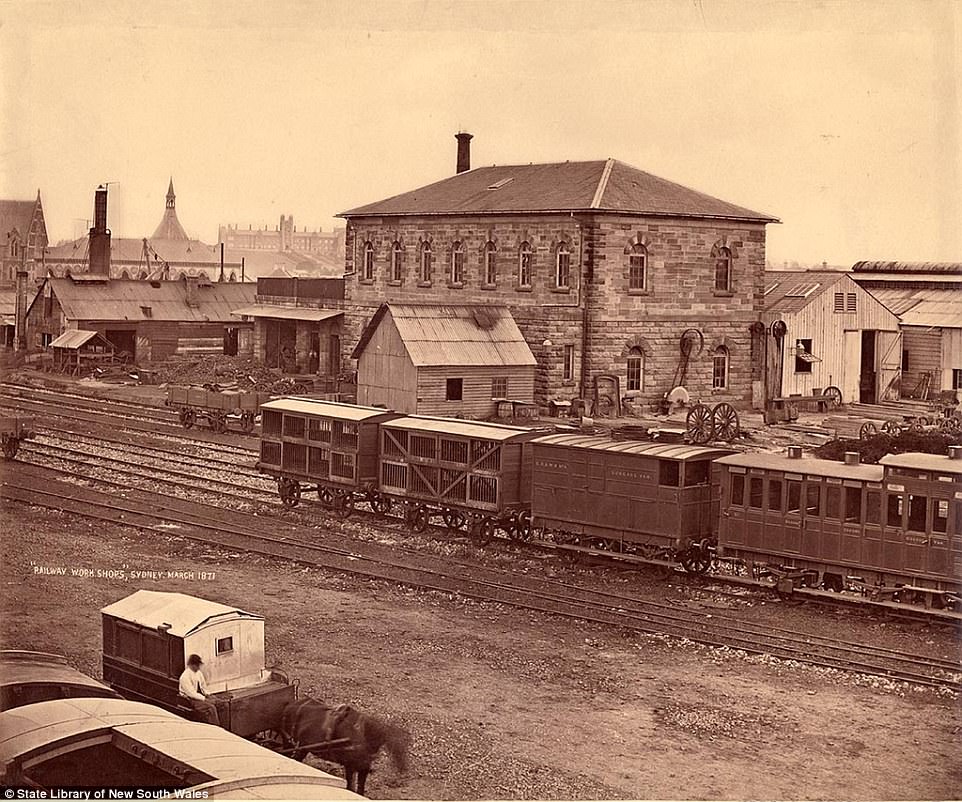 A brick railway workshop in Sydney taken in March 1871 showing parked carriages and horses and carts transporting goods to and from the workshop