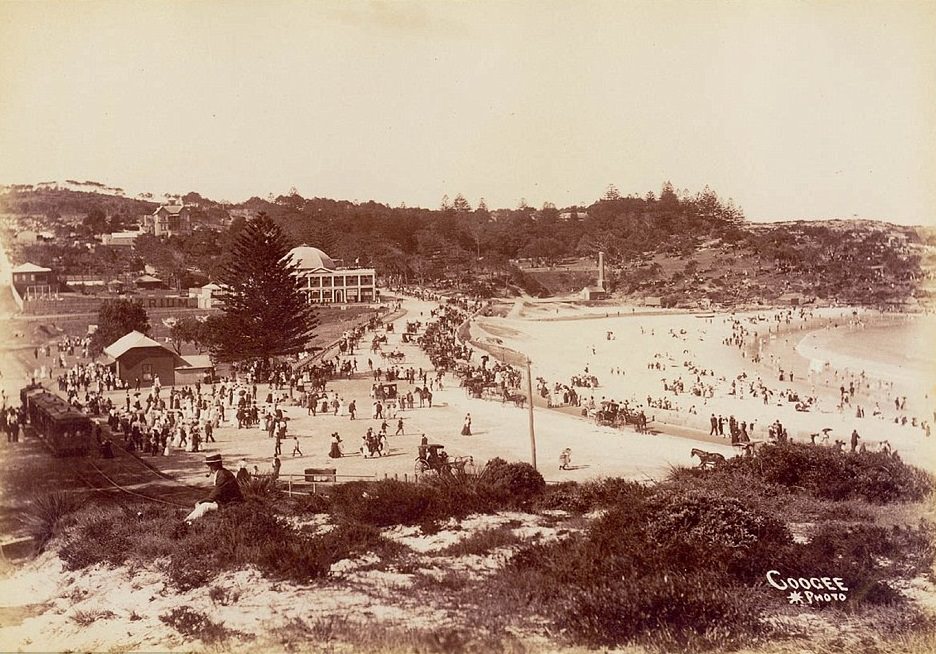 Coogee Beach circa 1905 shows a tram line running down the hill to the sandy beachfront, and Coogee Pavilion in the distance at one end of the beach