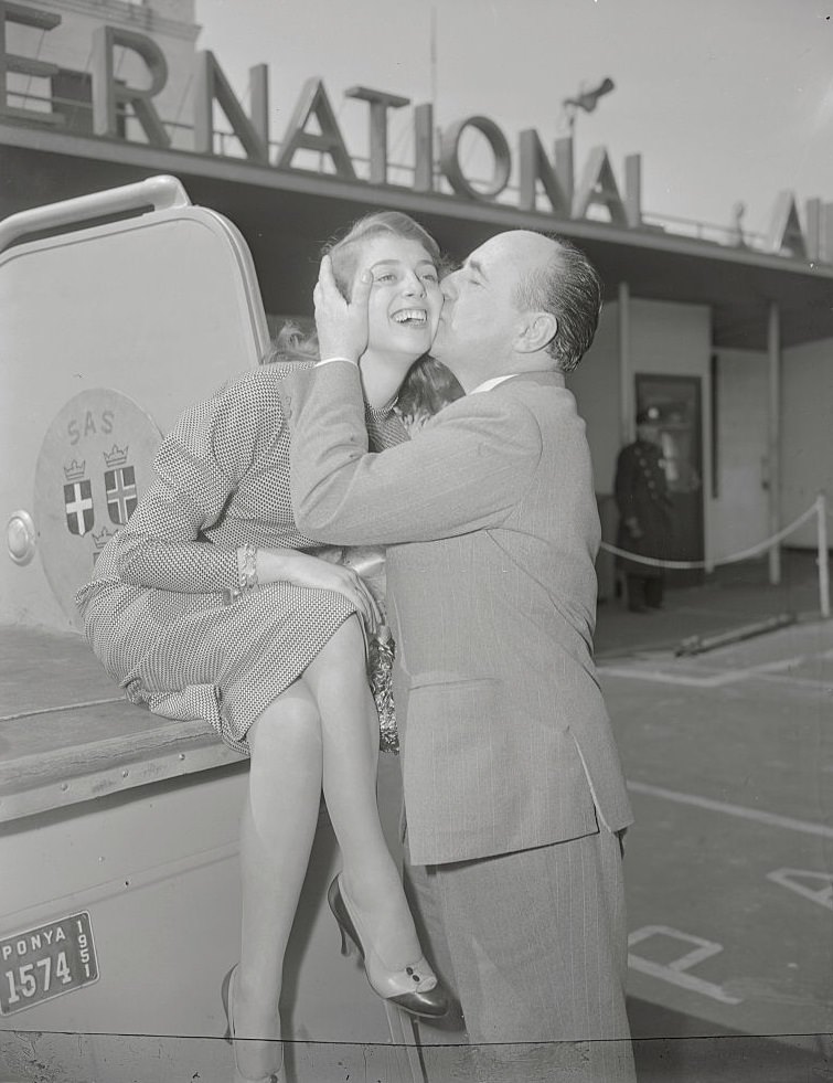 Pier Angeli being welcomed by Leonide Moguy with a kiss at Idlewild Airport, 1952