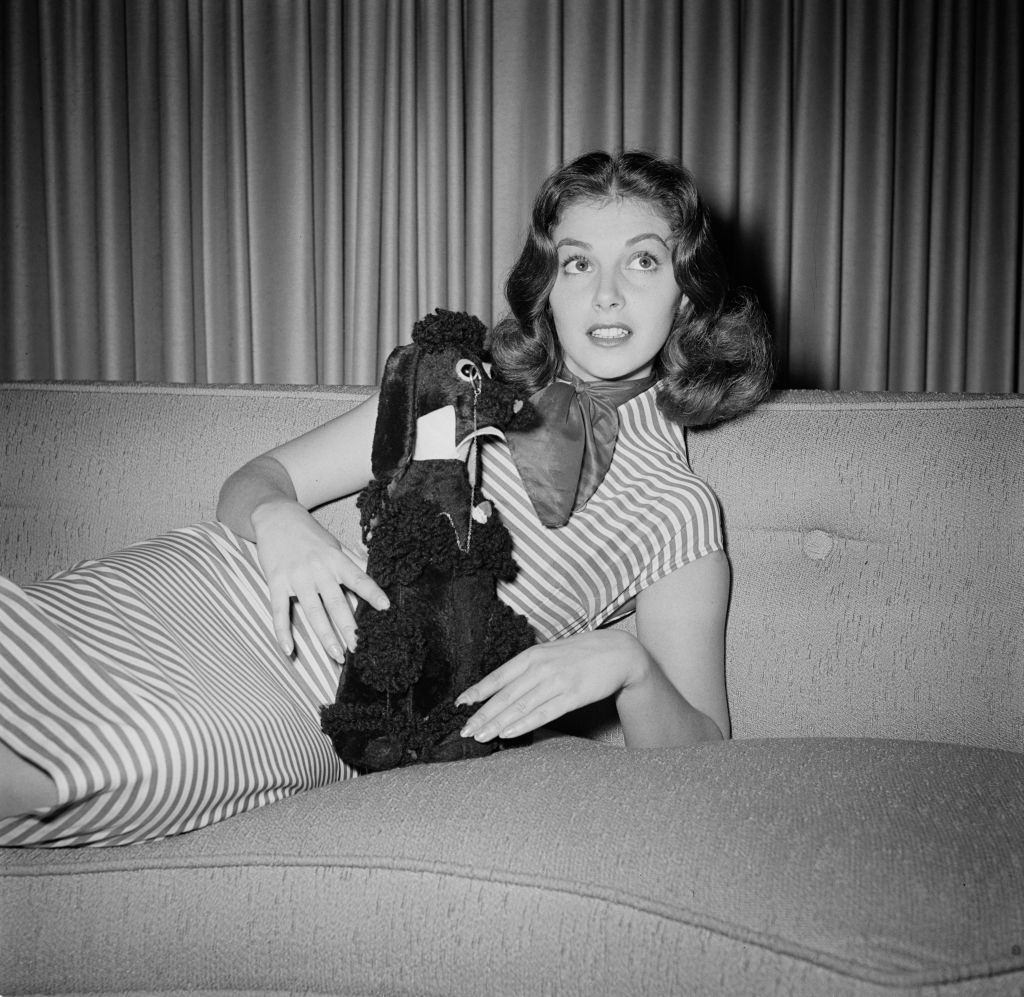 Pier Angeli holding a soft toy poodle with a monocle, 1955