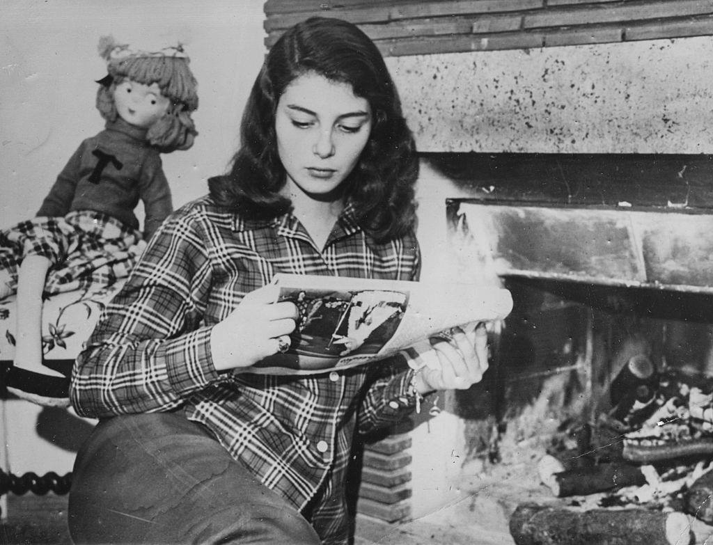 Pier Angeli reading a newspaper by the fire, after being given a five year contract in Hollywood by Metro Goldwyn Mayer, circa 1950.