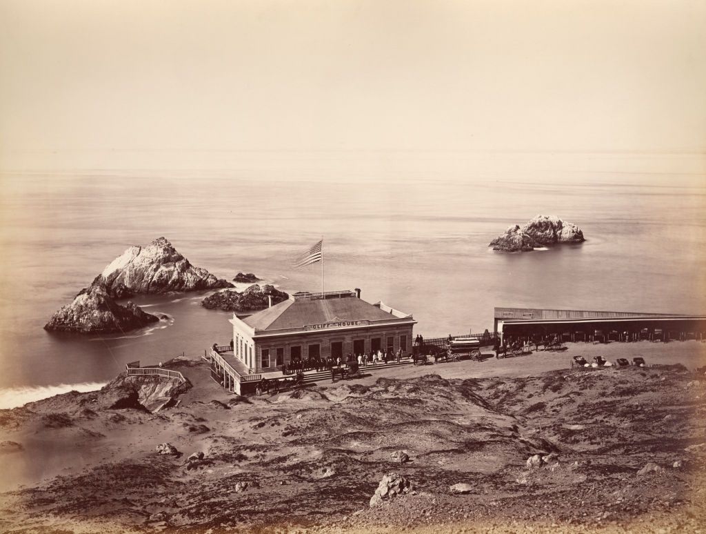 Horses and carriages on a path in front of Cliff House, San Francisco, 1869