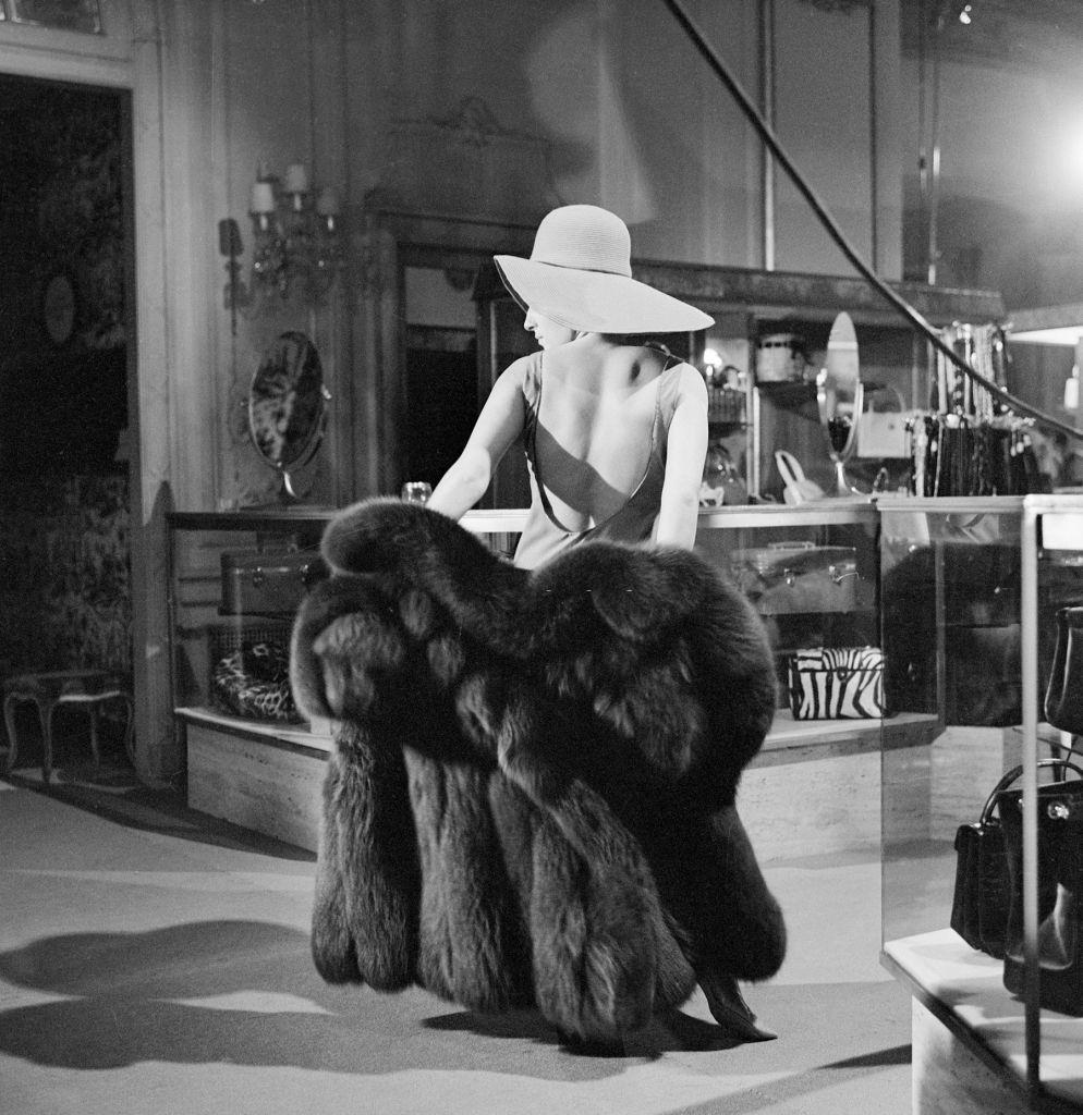 Barbra Streisand tries on a fur coat, 1965