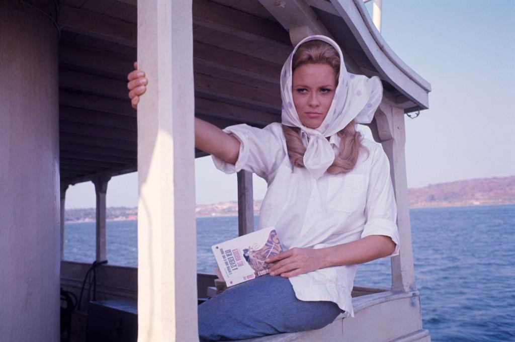 Faye Dunaway sitting in a boat on the set of the film The Extraordinary Seaman, 1969
