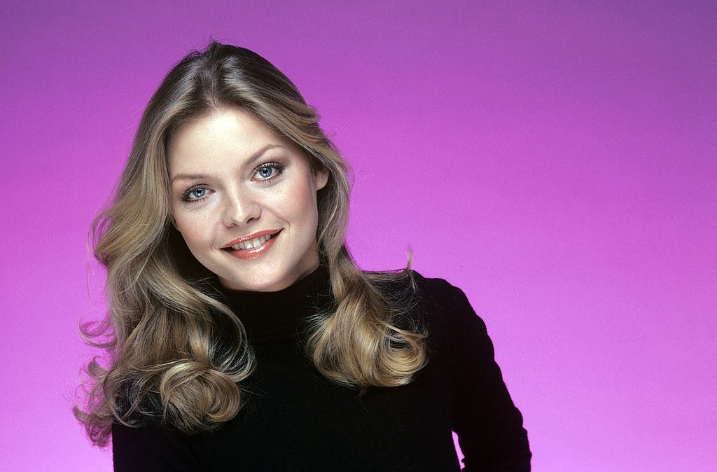 Michelle Pfeiffer smiling while resting her chin on her hand