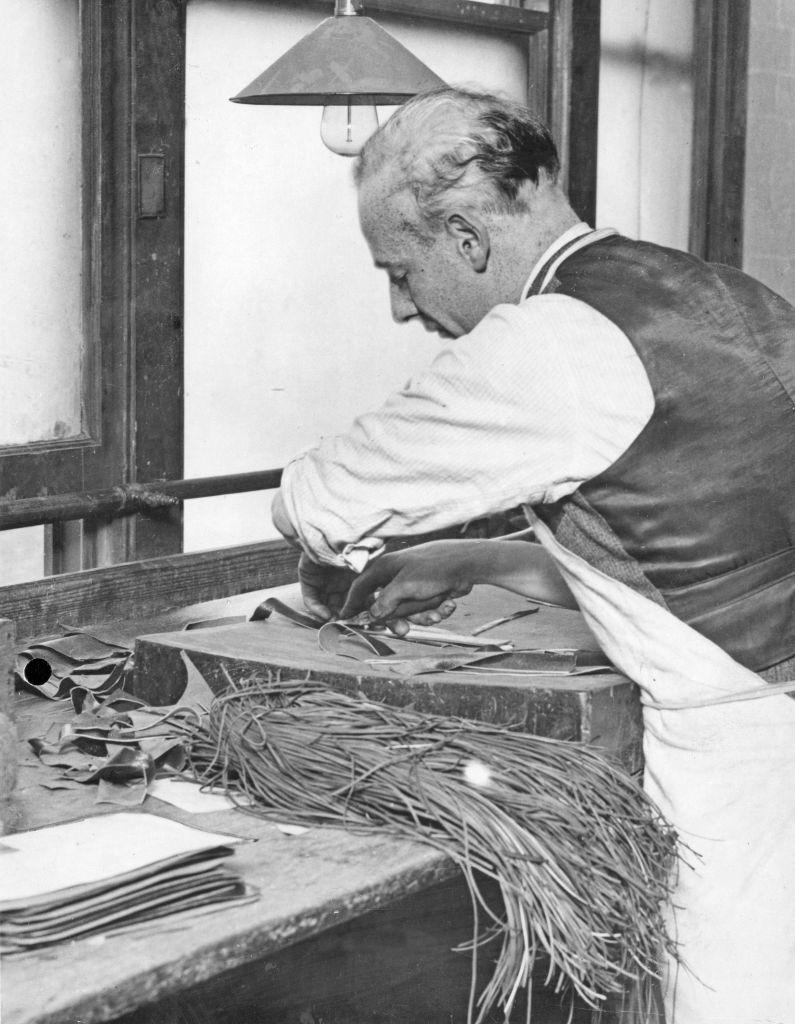 A skilled leather cutter carries out the first stage of the manufacture of a handbag by cutting the leather to a template, 9th October 1931.