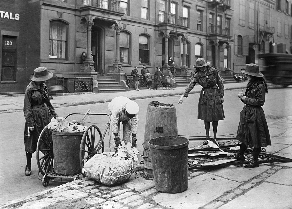 Girl Scouts taking notes on methods of a New York street cleaner, 1930s.