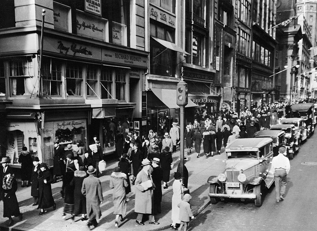 View of pedestrian and vehicle traffic at the intersection of 42nd Street and 5th Avenue, New York City, 1930s.