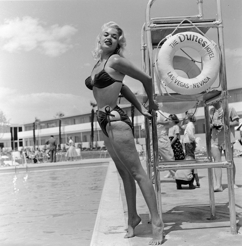 Jayne Mansfield poses in a bikini by a lifeguard chair at the Dunes Hotel, Las Vegas, 1950s