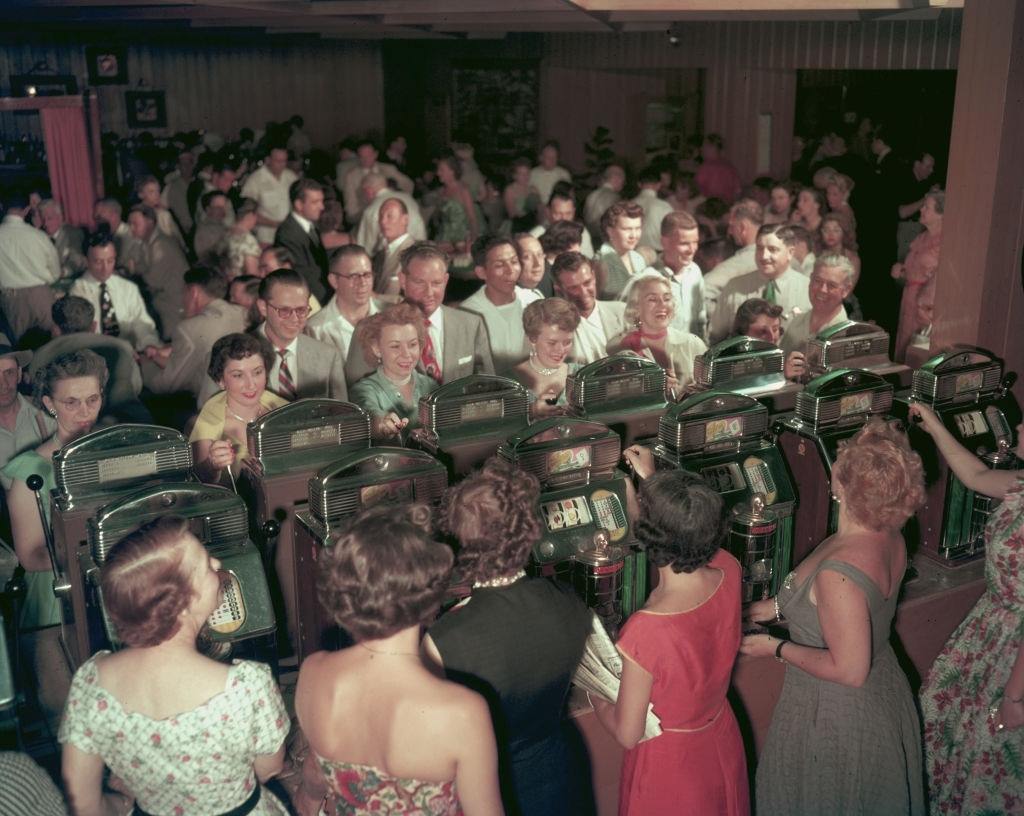 Women playing Jennings Sun Cheif Slot Machines in a crowded room at the Desert Inn Casino, Las Vegas, 1953