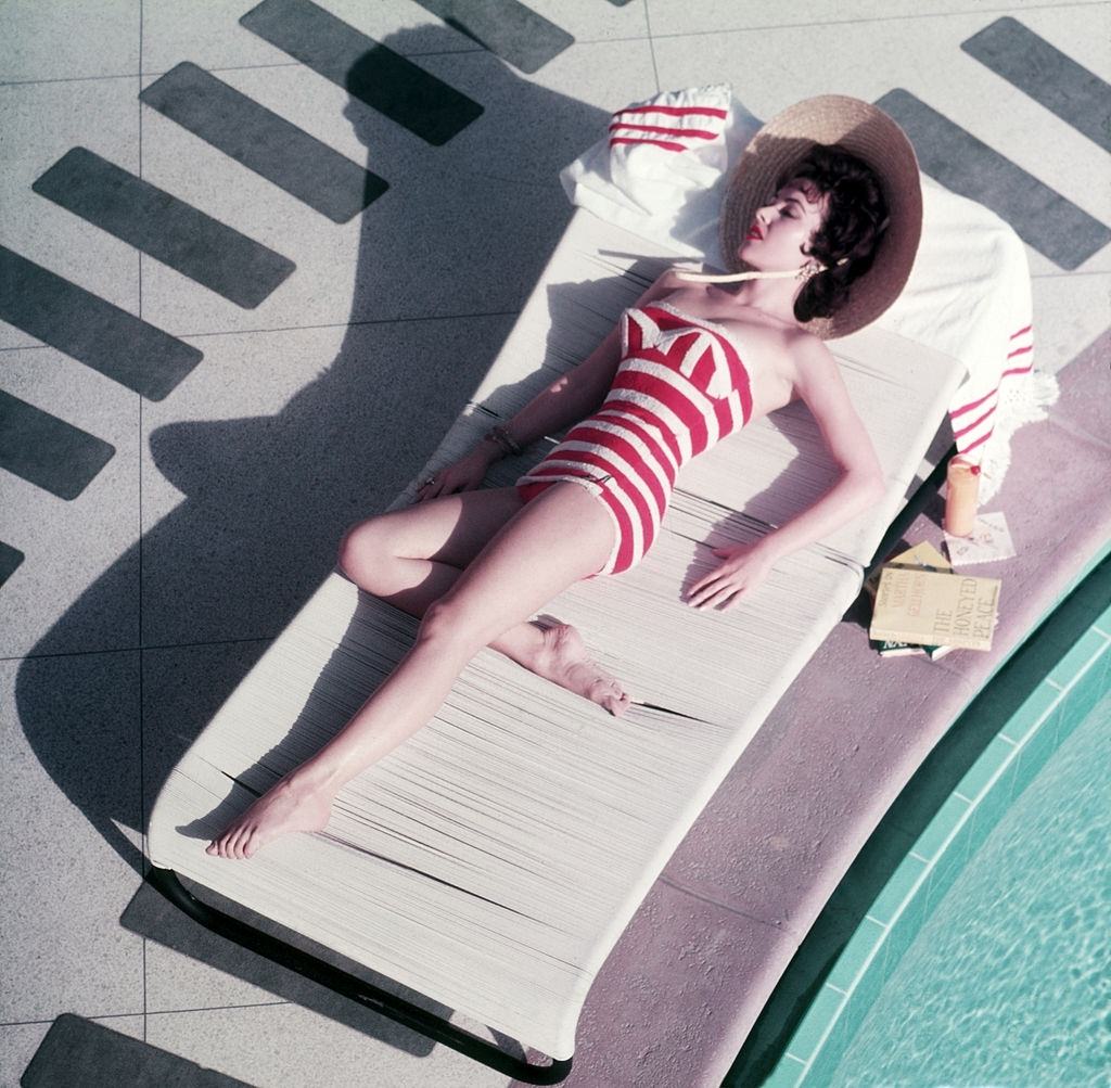 Austrian actress Mara Lane lounging by the pool in a red and white striped bathing costume at the Sands Hotel, Las Vegas, 1954.
