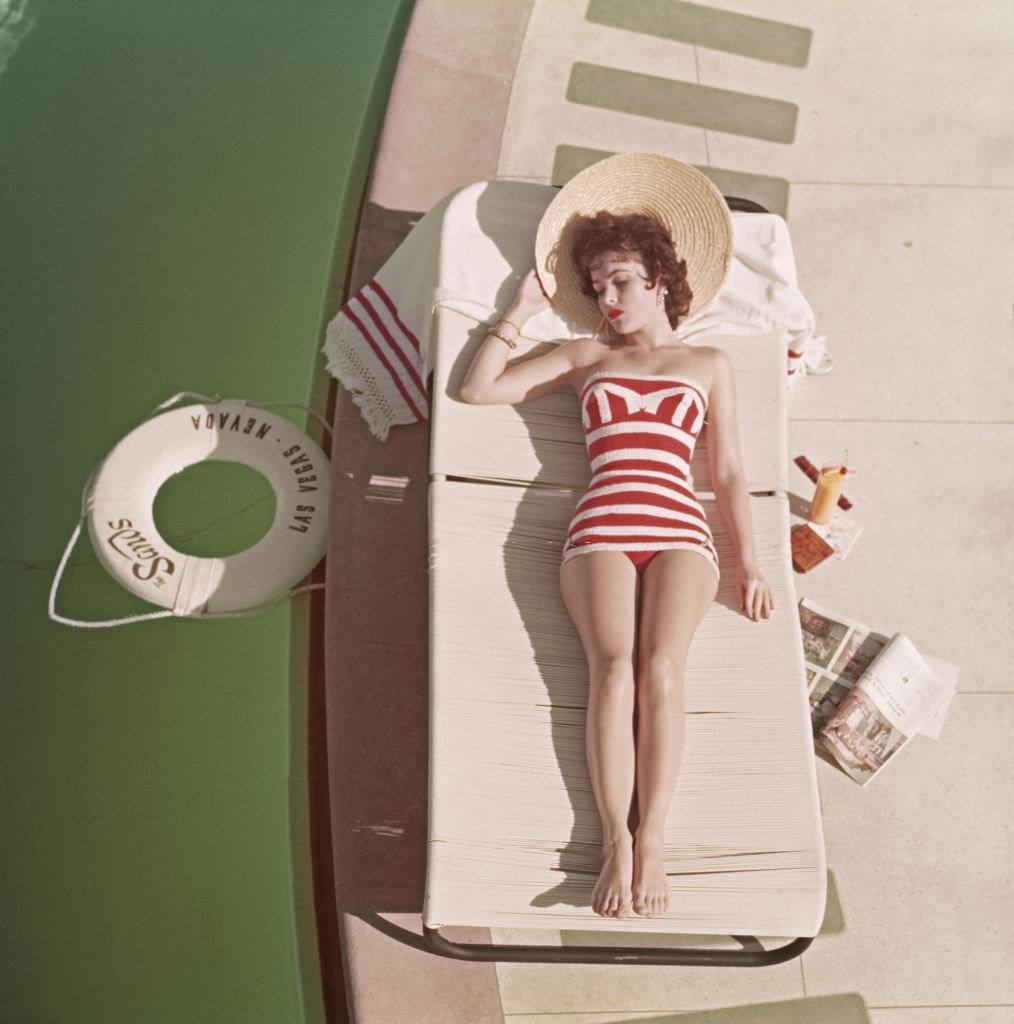 Austrian actress Mara Lane lounging by the pool in a red and white striped bathing costume at the Sands Hotel, Las Vegas, 1954.