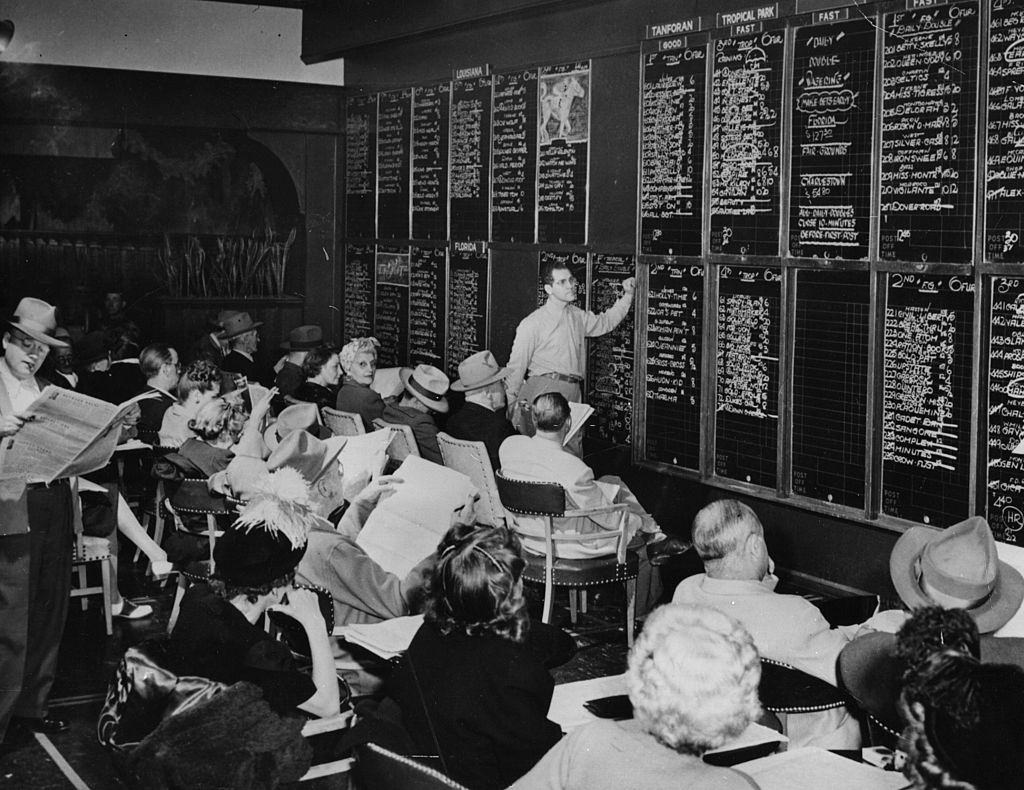 A crowd checks the results of horse races all over the USA at a Las Vegas betting shop, 1954.
